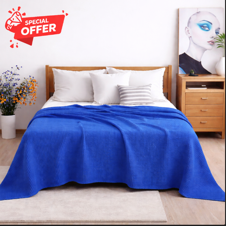 Royal blue cotton thermal blanket draped over a bed.