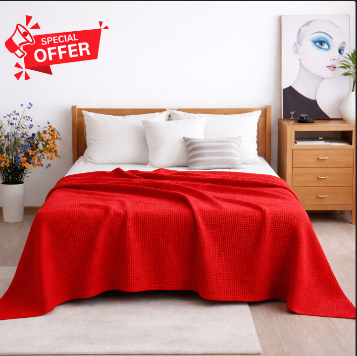 Red cotton thermal blanket draped over a bed.