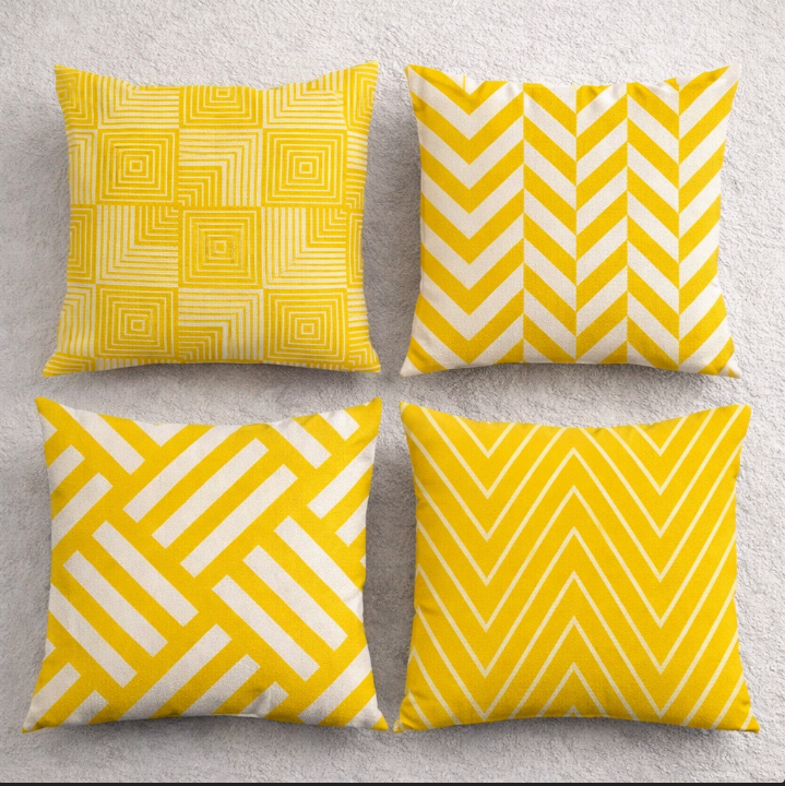 Four yellow and white cushion covers with square, chevron and diagonal geometric patterns.