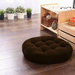 Round dark brown tufted floor cushion on a wooden floor.