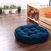 Round blue tufted floor cushion on a wooden floor.