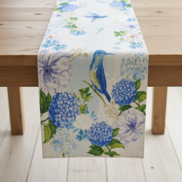 Cream table runner with blue flowers and colourful bird illustrations.