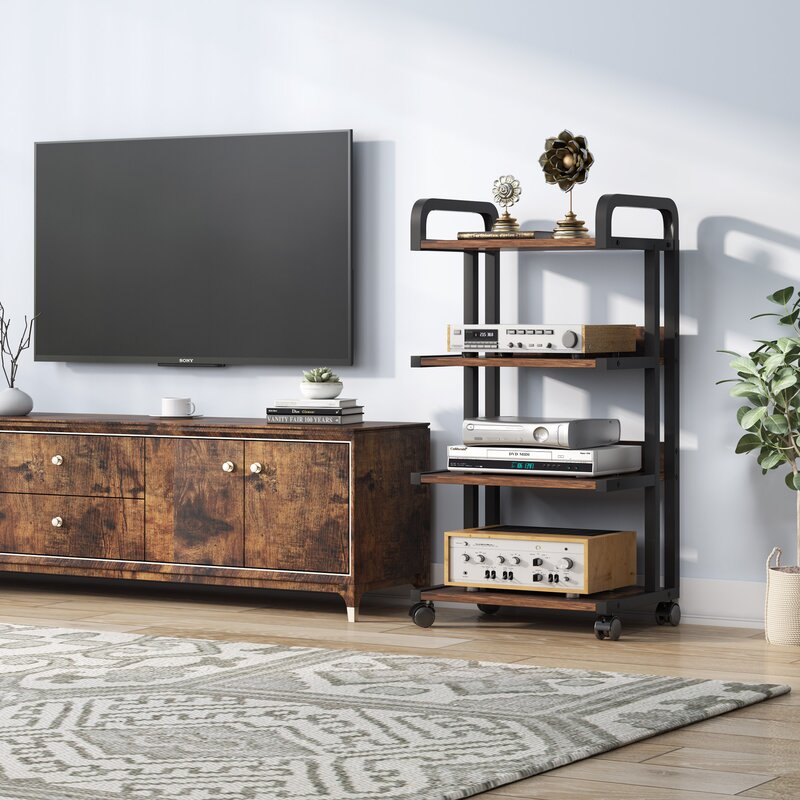 Four-tier rolling rack with a black frame and brown shelves holding audio and media equipment beside a television.