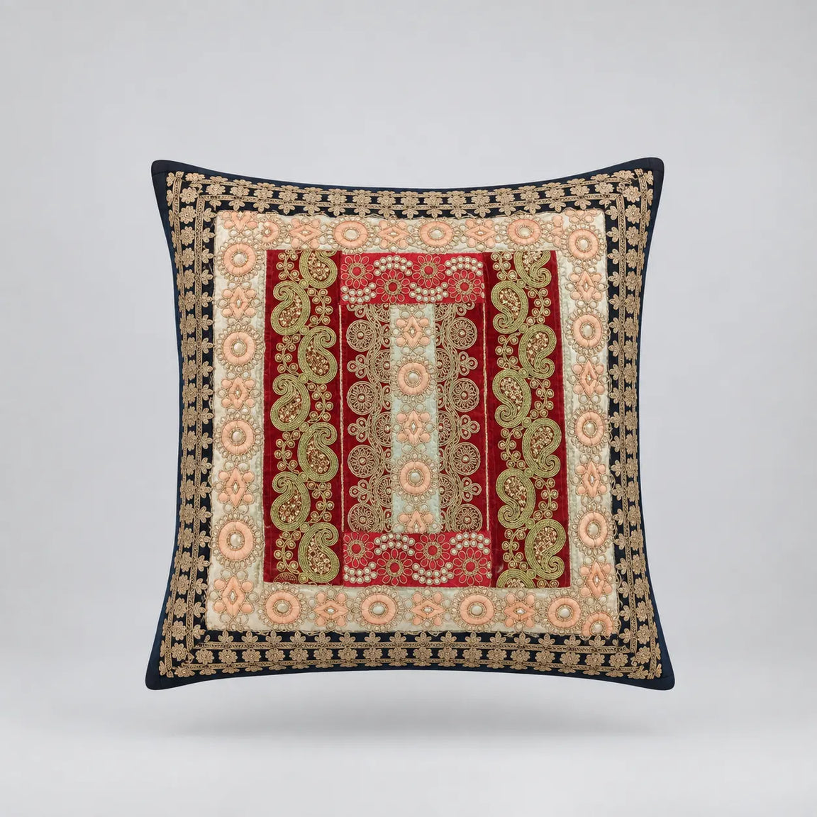 Dark-bordered cushion cover with ornate red, cream and pale gold coloured rectangular panels.