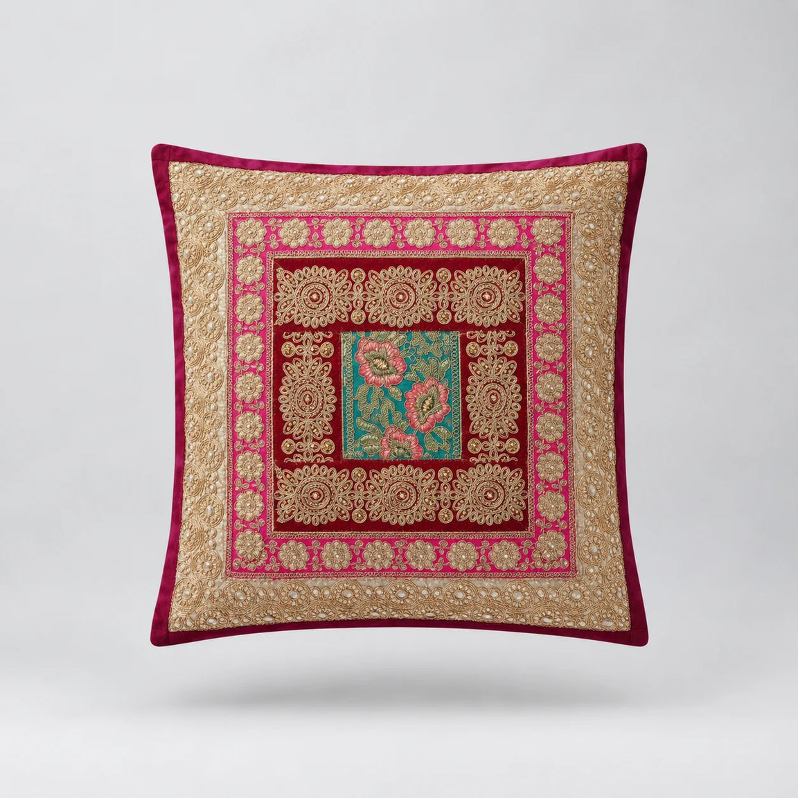 Burgundy-bordered cushion cover with layered pale gold coloured and red frames around a teal floral centre.