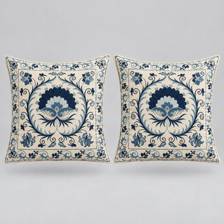 Two square decorative throw pillows with a blue and cream floral damask pattern, displayed side-by-side against a neutral light gray background.