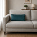 Plain rectangular teal filled cushion on a pale sofa.