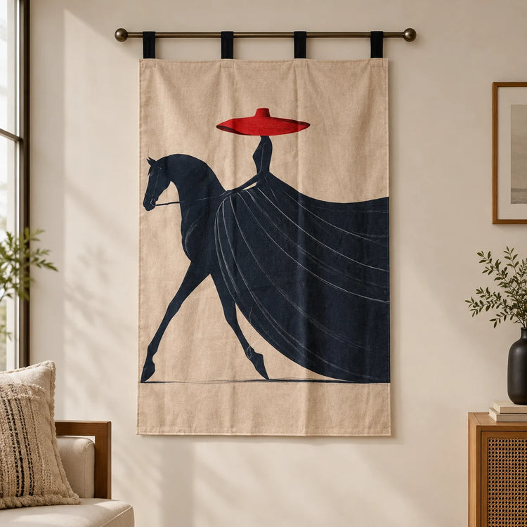 A beige wall hanging or tapestry with a stylized dark navy horse and rider graphic and a bright red hat, suspended from a metal rod in a softly lit room.
