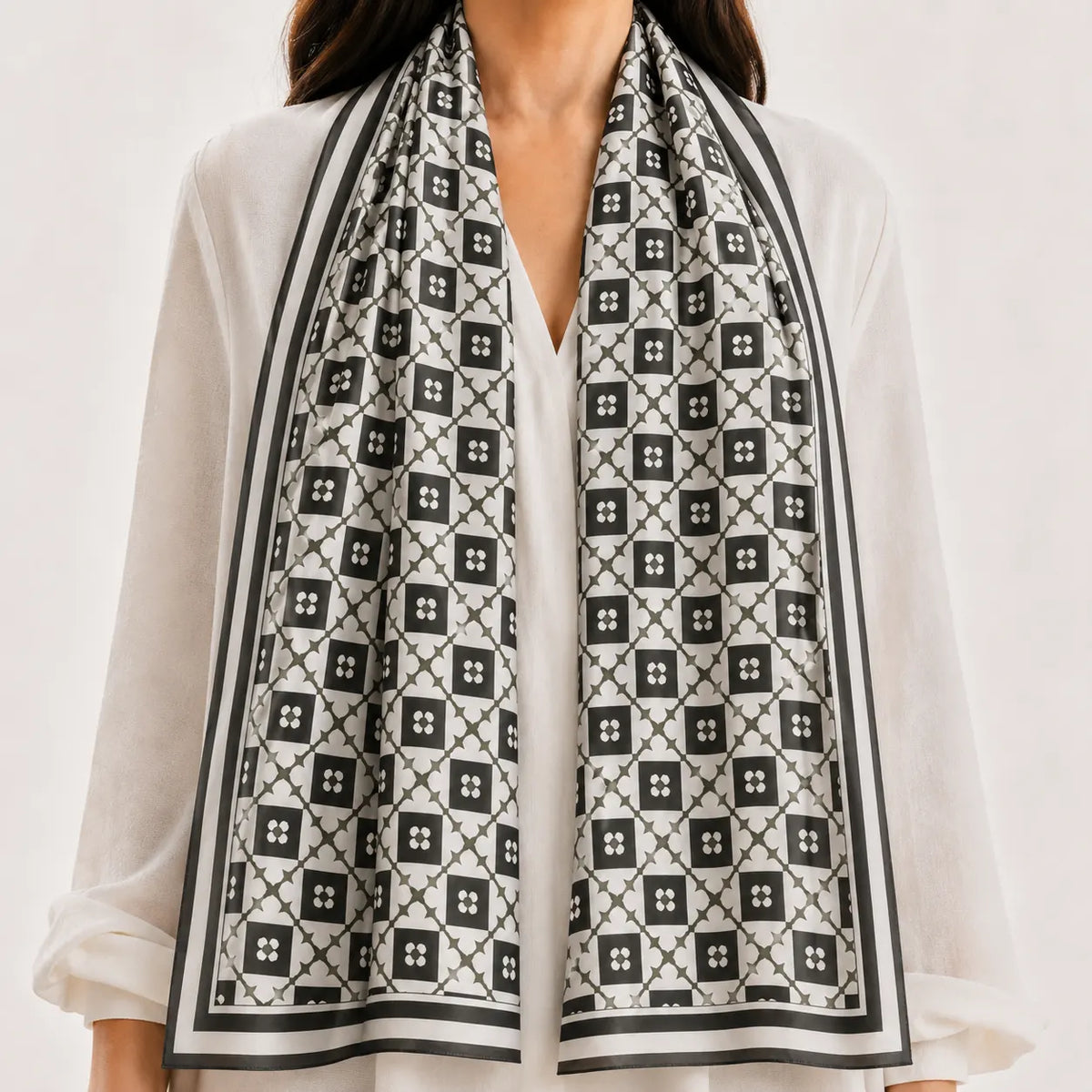 A black and white patterned scarf draped over a woman's shoulders, styled with a white blouse against a clean white background.