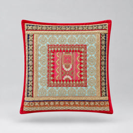 Red-bordered cushion cover with cream and green ornamental bands and a small patterned red centre.