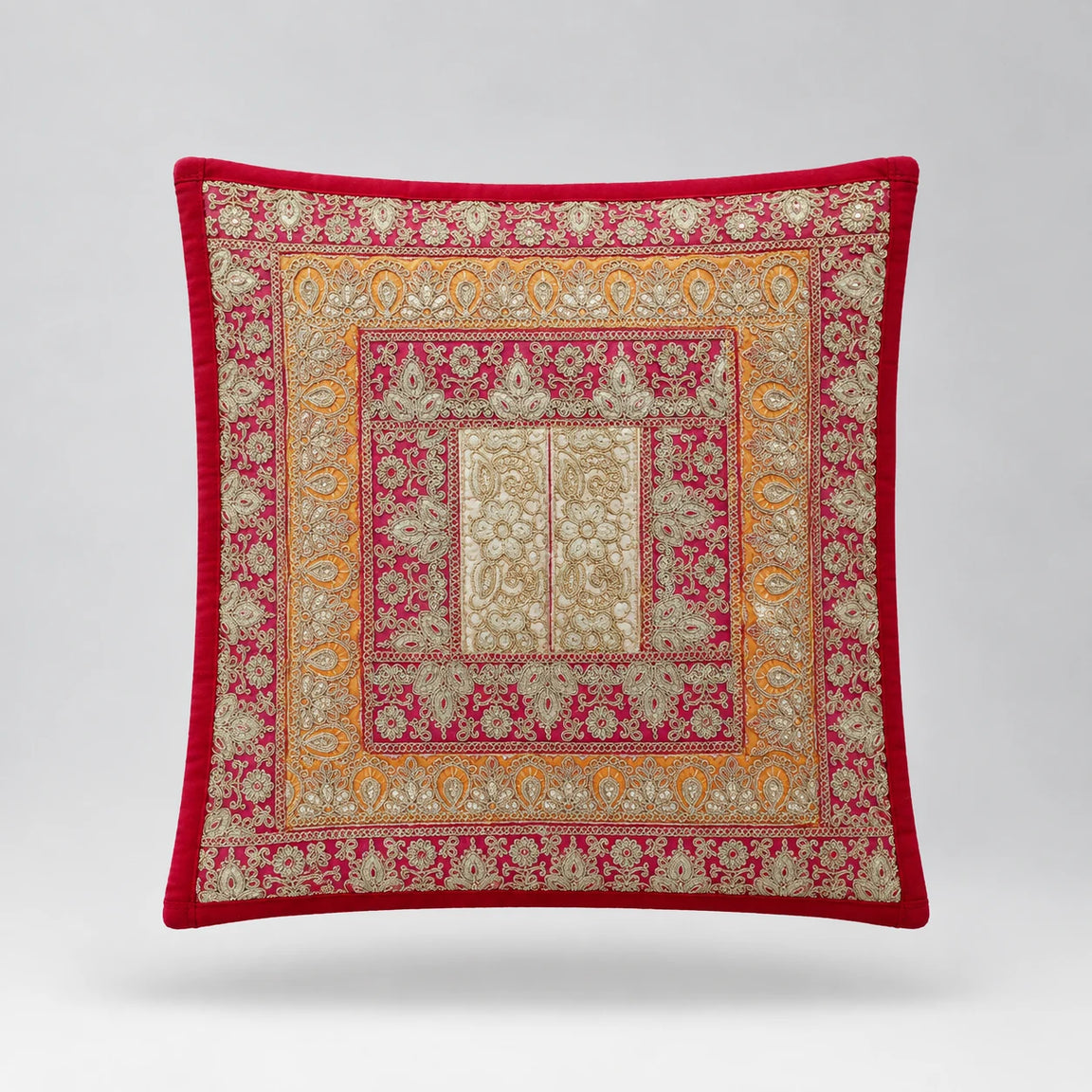 Red-bordered cushion cover with pink and gold coloured ornamental frames around a pale centre.