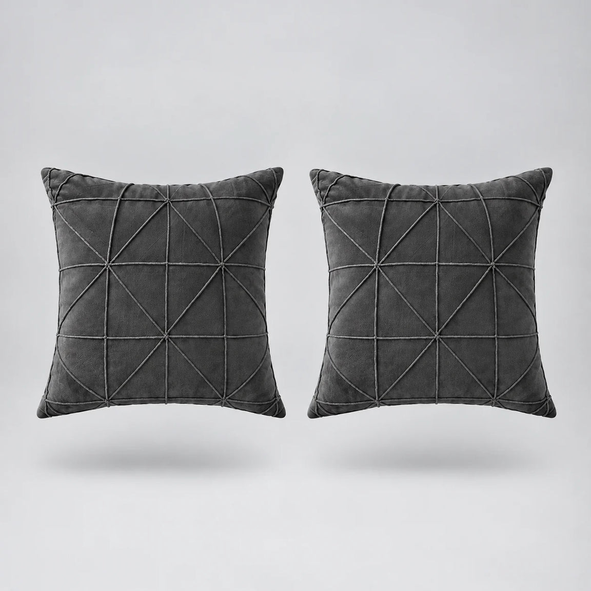 two gray velvet cushions floating on a light grey surface