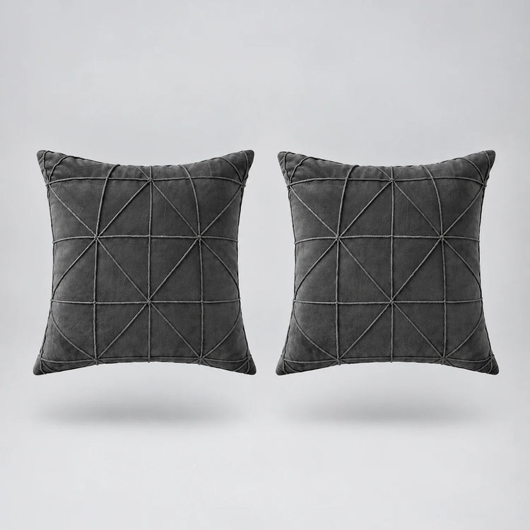 two gray velvet cushions floating on a light grey surface