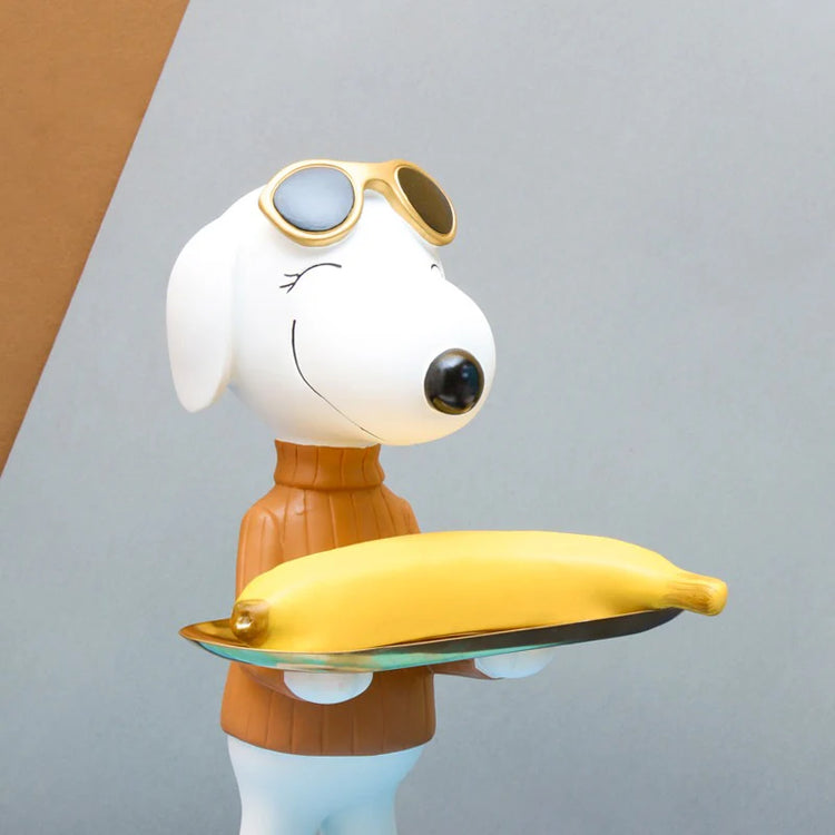 White dog figurine in an orange top holding a gold-coloured tray.