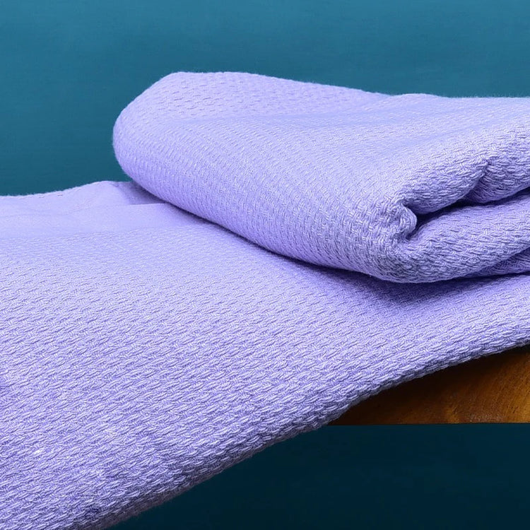 Close-up of a folded lilac textured cotton thermal blanket.