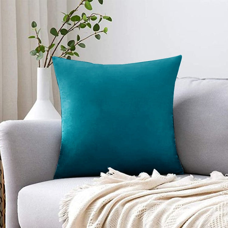 Plain teal filled cushion displayed on a white sofa.