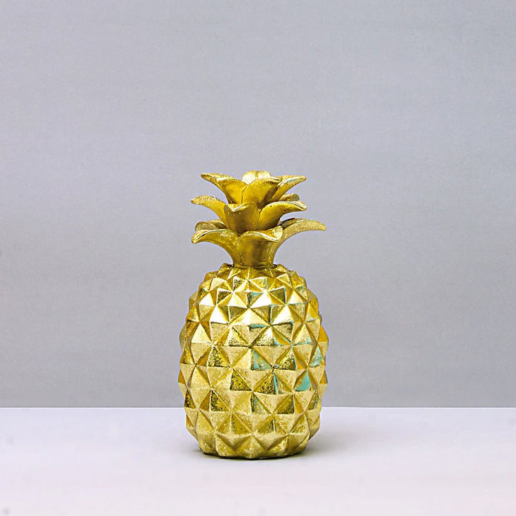 Gold-coloured pineapple ornament against a plain background.