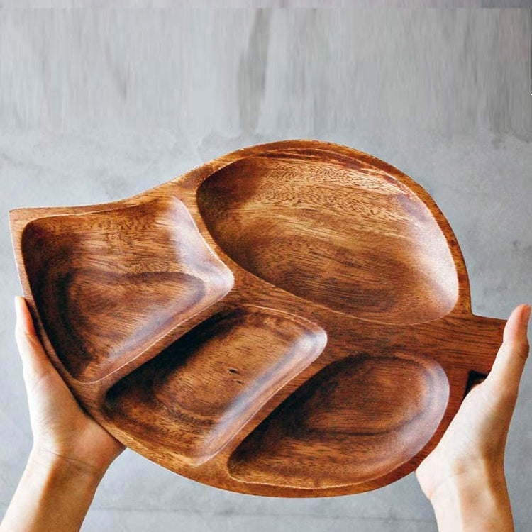 Hands holding a brown leaf-shaped serving tray with four recessed compartments