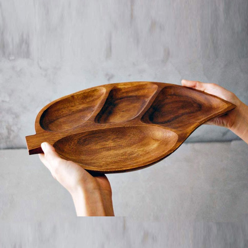 Side view of hands holding a brown compartmented leaf-shaped tray