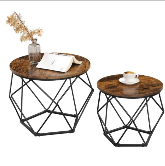 Two round brown coffee tables with black geometric bases holding a vase, book and cup.