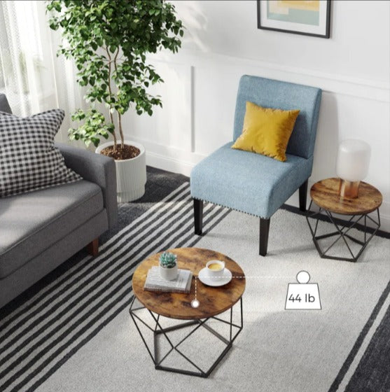 Round brown tables with black geometric bases positioned beside a sofa and blue chair.
