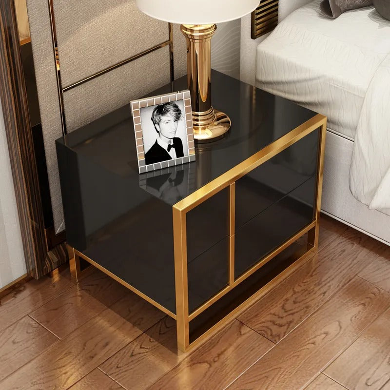 Overhead view of a black bedside cabinet with gold-colored frame beside a bed.