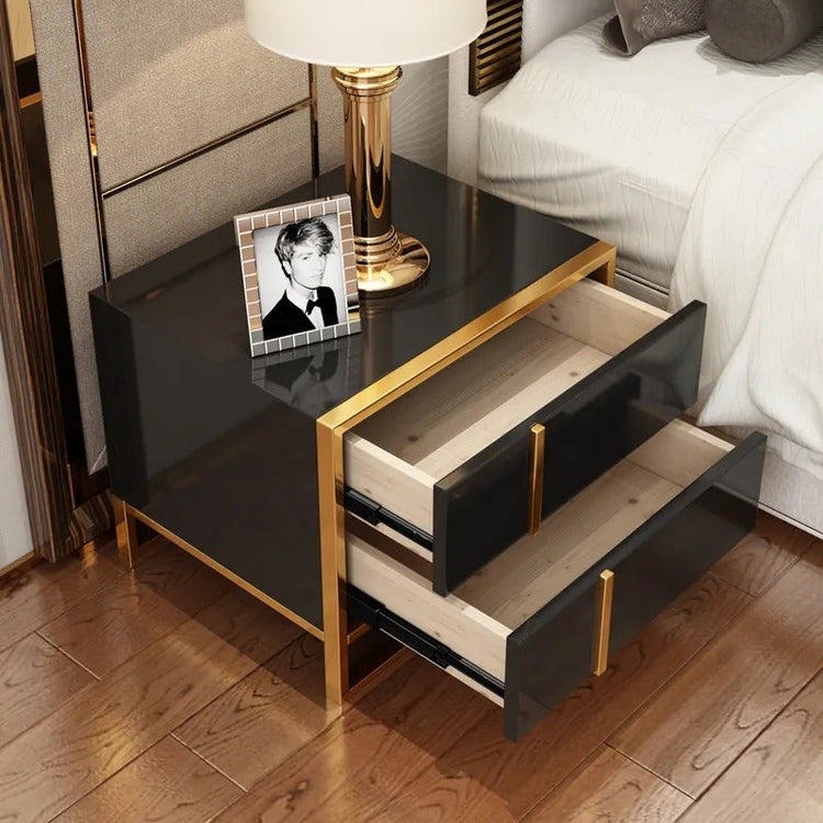 Black bedside cabinet with both drawers open beneath a lamp and framed photograph.