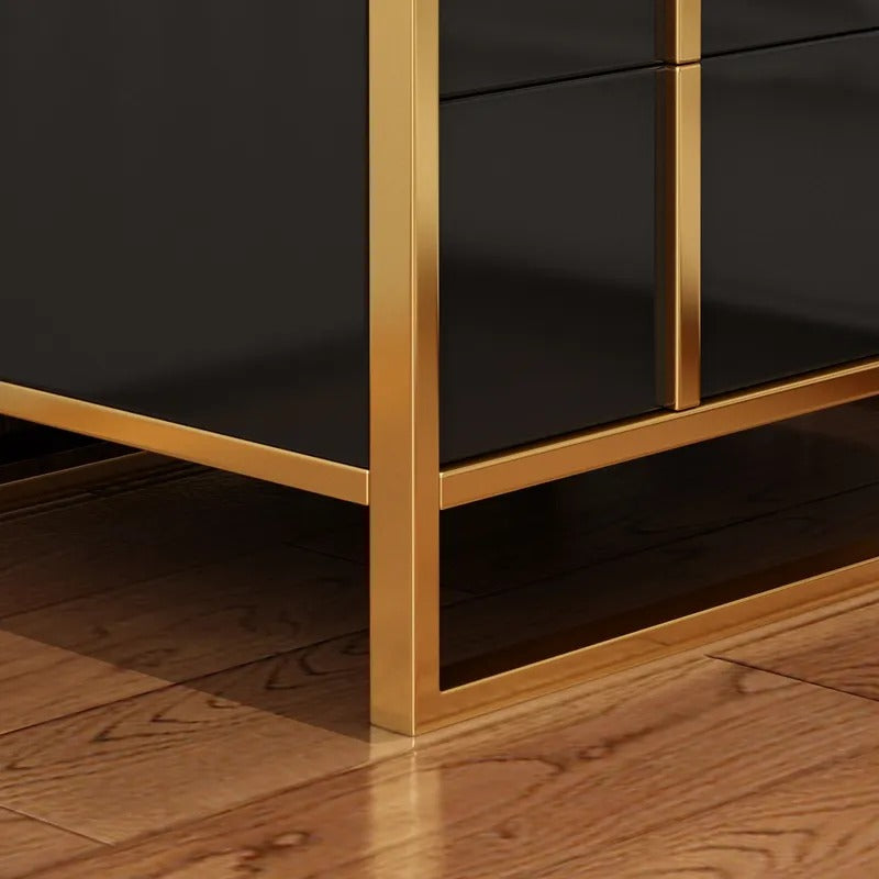 Close-up of the black drawer fronts and gold-colored base frame of a bedside cabinet.
