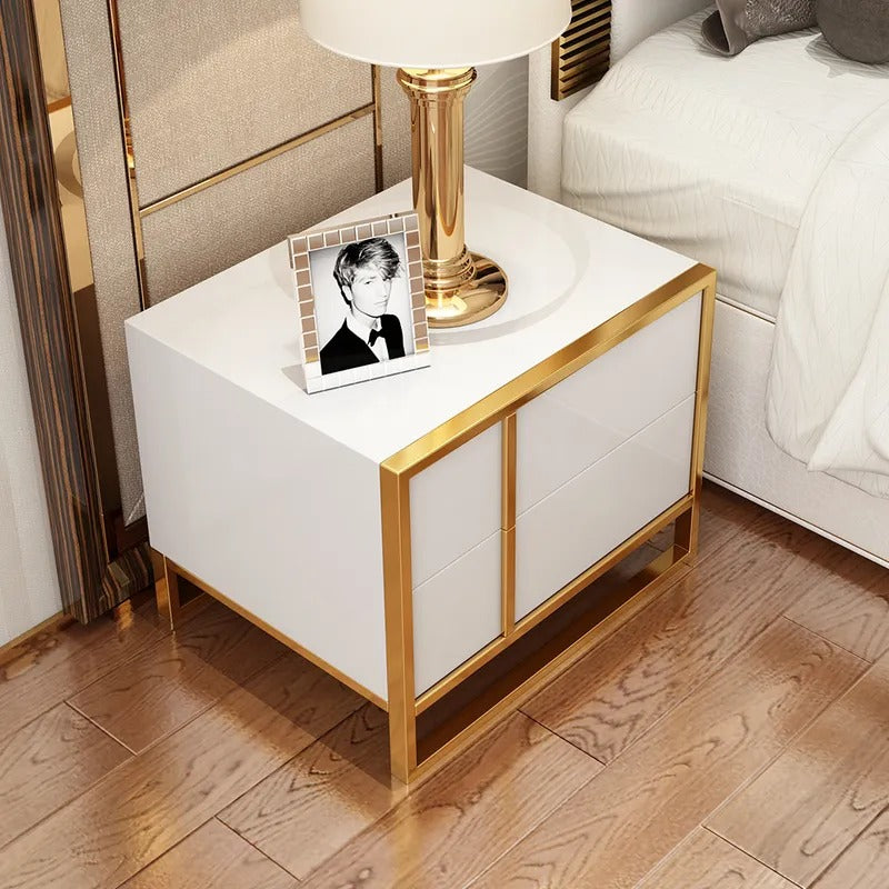 Overhead view of a white bedside cabinet with gold-colored frame beside a bed.