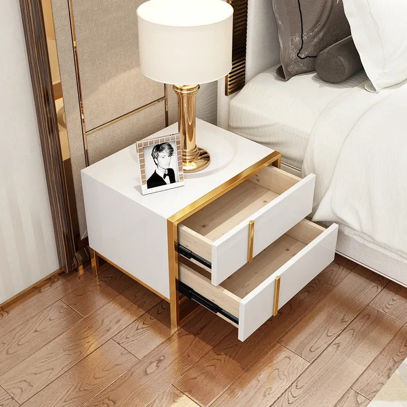 White bedside cabinet with both drawers open beneath a lamp and framed photograph.