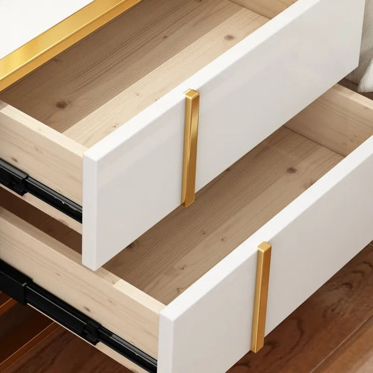 Close-up of two open white bedside cabinet drawers with gold-colored handles.