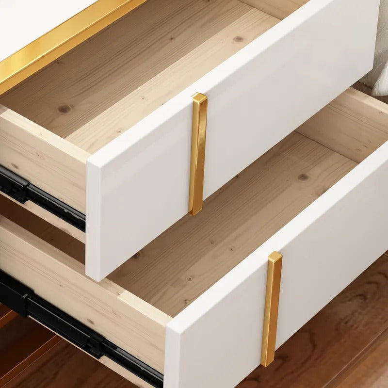 Close-up of two open white bedside cabinet drawers with gold-colored handles.