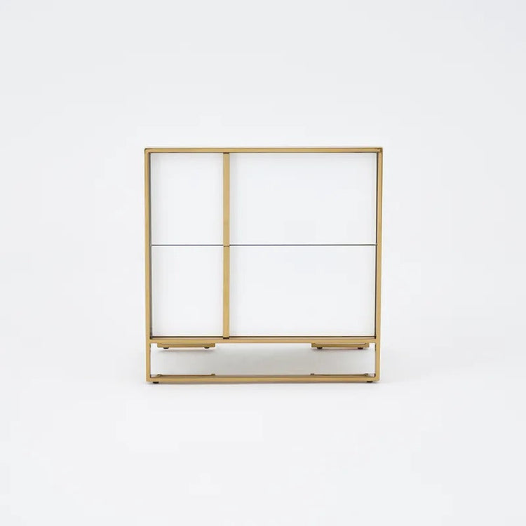 Front view of a white two-drawer bedside cabinet with gold-colored trim.