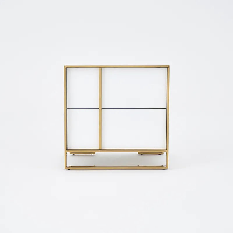 Front view of a white two-drawer bedside cabinet with gold-colored trim.