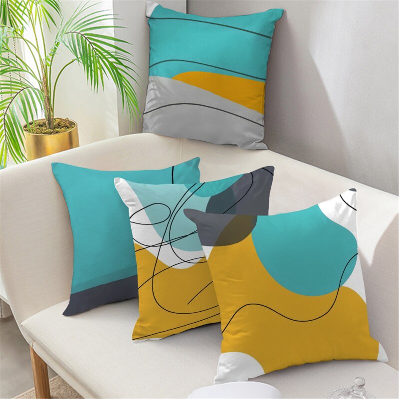 Teal, mustard, grey and white abstract cushion covers arranged on a sofa.