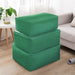 Three dark green fabric storage cubes stacked beside a sofa.