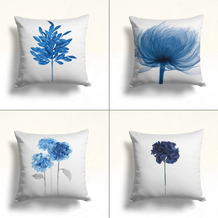 Four white cushion covers with different blue floral and leaf designs.