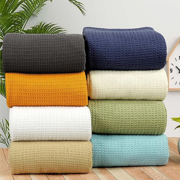 Stacks of waffle-weave cotton thermal blankets in assorted colours.