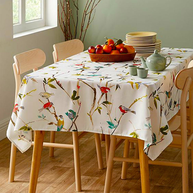 Cream tablecloth with colourful birds and delicate branch motifs.