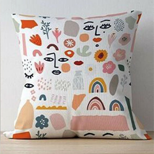White cushion cover with assorted face, flower, rainbow and abstract illustrations.