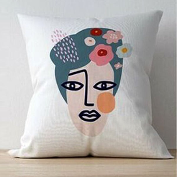 White cushion cover with an abstract face and flowers arranged in the hair.