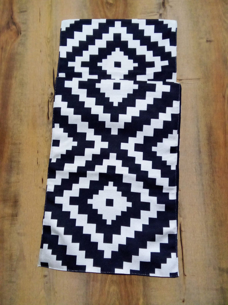 Overhead view of a black and white diamond-pattern table runner.