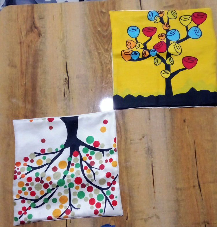 Two colourful tree print cushion covers laid flat on a wooden surface.