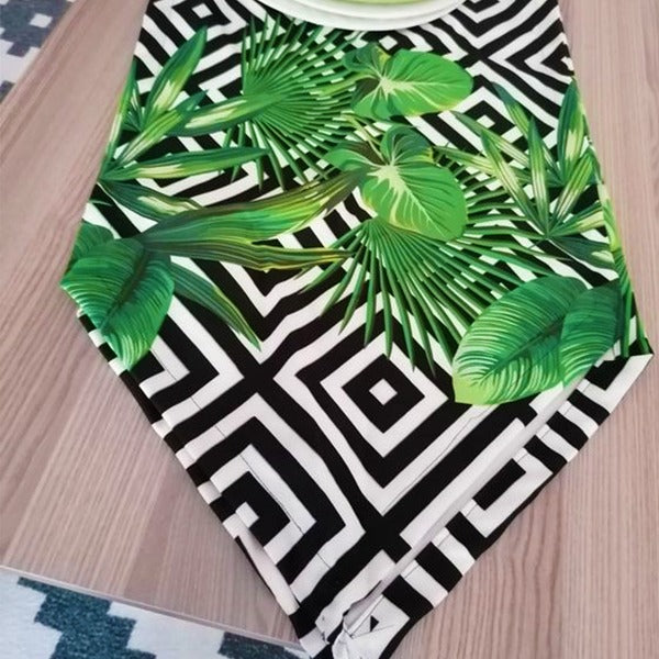 Close view of green tropical leaves over black and white diamonds on a table runner.