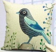 Cream cushion cover with a dark blue and teal bird among delicate leafy sprigs.