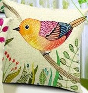 Close view of a cream cushion cover with a yellow and pink bird among branches.