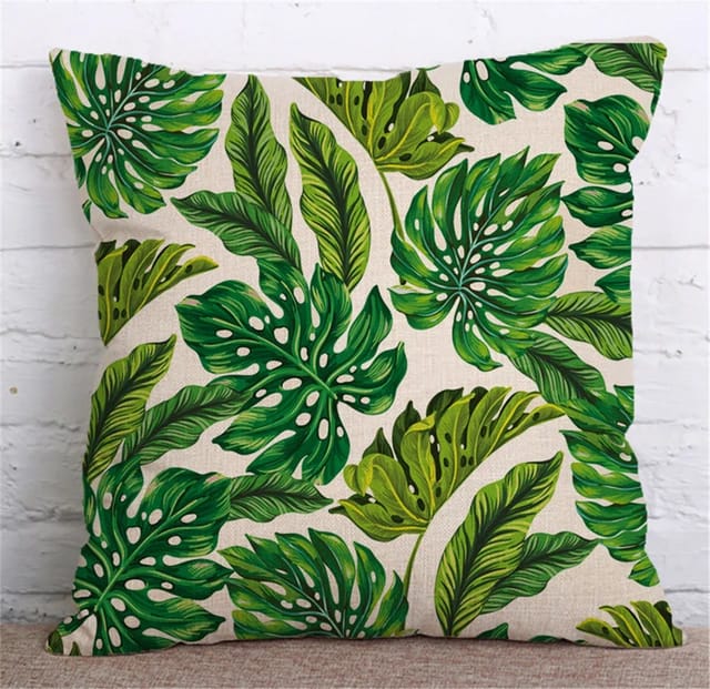 Cream cushion cover with a repeating green and yellow tropical leaf pattern.