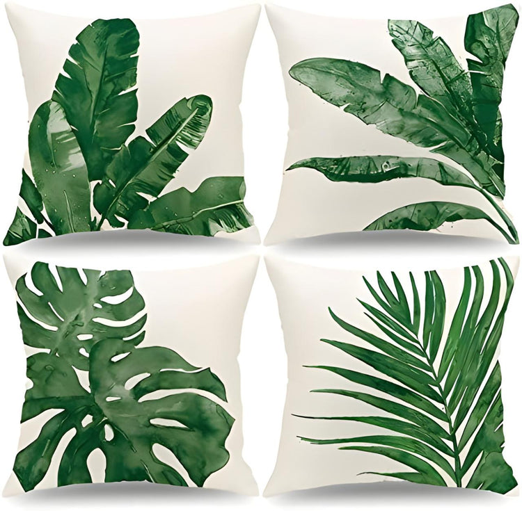 Four cream cushion covers with large green tropical leaf prints.
