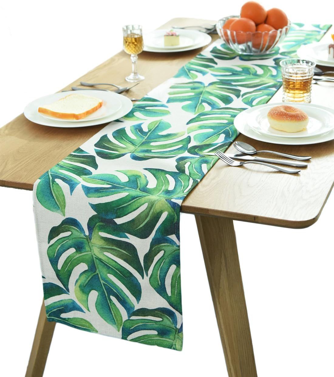 Green tropical-leaf table runner displayed on a light wood-tone dining table