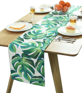 Green tropical-leaf table runner displayed on a light wood-tone dining table